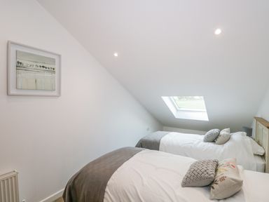 A bedroom with two single beds under a skylight window at Coney Garth Cottage in Beckermet