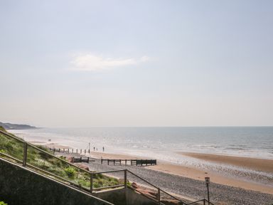 A view of a beach with a pebble shore and a stair railing in the foreground at Coney Garth Cottage in Beckermet