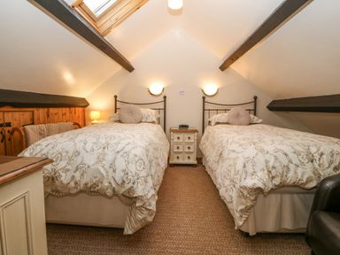 A bedroom with two single beds under a slanted ceiling with exposed beams at Bwthyn Ael Y Bryn in Criccieth