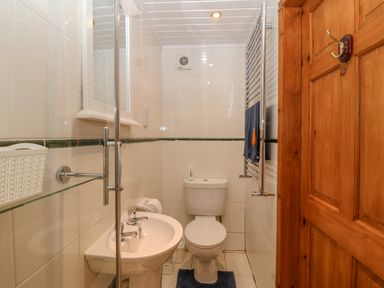 A small bathroom with a toilet sink and towel rack at Bwthyn Ael Y Bryn in Criccieth