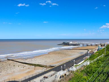 A coastal view with a pebble beach a pier and a road with benches and stairs at Howards Hill West in Cromer