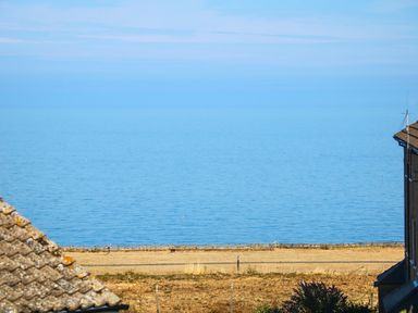 A coastal view with blue sea a dry grassy area and rooftops at Howards Hill West in Cromer