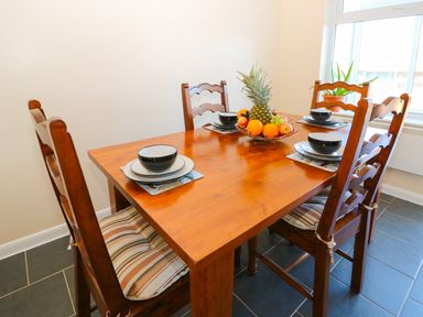 A dining room with a wooden table set with bowls and plates and a fruit bowl at Howards Hill West in Cromer