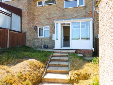 A back garden with steps leading to a glass door entrance of a brick house at Howards Hill West in Cromer