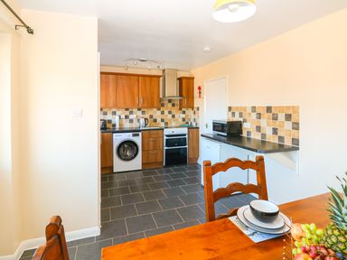 A kitchen with wooden cabinets appliances and dining furniture at Howards Hill West in Cromer