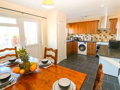 A kitchen with wooden cabinets a dining table with fruit bowl and black and white crockery at Howards Hill West in Cromer