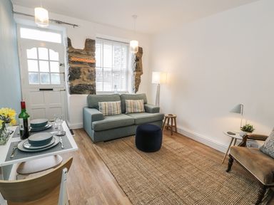 A living room with a sofa table set with plates and a bottle of wine and a chair at Llys Madoc in Porthmadog