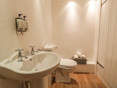 A bathroom with a sink toilet and a box of toilet rolls on the floor at Llys Madoc in Porthmadog