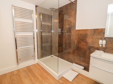 A bathroom with a glass shower enclosure a white towel rail and a white vanity unit at Llys Madoc in Porthmadog