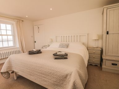 A bedroom with a double bed bedside tables lamps a wardrobe and a window at Searles in Lympstone