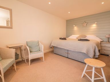 A bedroom with two chairs a small table a bed with bedding and towels and a star decoration on the wall at Searles in Lympstone