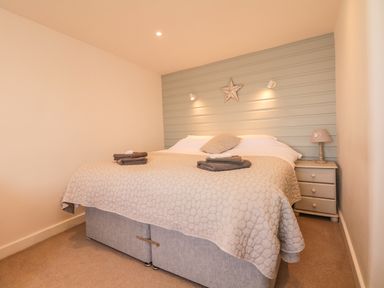 A bedroom with a double bed bedside table lamp and folded towels at Searles in Lympstone