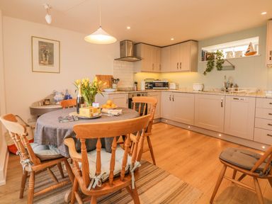 A kitchen with a round dining table and wooden chairs at Searles in Lympstone