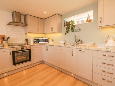 A kitchen with beige cabinets oven microwave toaster sink and decorative items at Searles in Lympstone