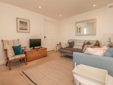 A living room with a sofa chairs a wooden chest and a mirror at Searles in Lympstone
