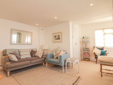 A sitting room with sofas a chair a floor lamp a small table and a bookshelf at Searles in Lympstone