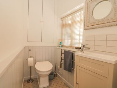A bathroom with a toilet a sink a window with blinds and a mirror at Searles in Lympstone