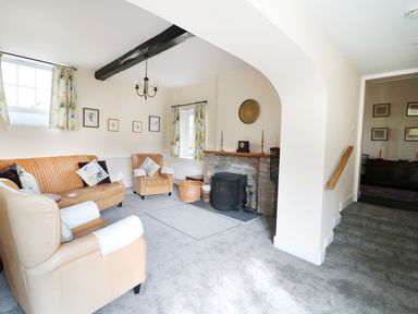 A living room with beige leather sofas a fireplace and floral curtains at Glebe House in Wells
