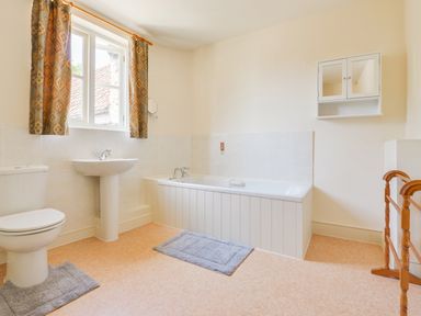 A bathroom with bathtub toilet sink window with curtains and wall cabinet at Glebe House in Wells