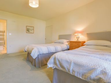 A bedroom with two single beds a bedside table with a lamp and a framed picture on the wall at Glebe House in Wells
