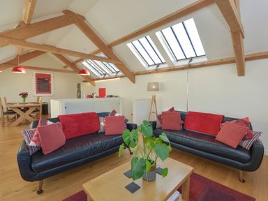 A living room with two black leather sofas and a wooden coffee table under skylights at Old Armoury Barn Ashburton