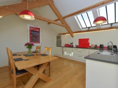 A kitchen and dining area with wooden beams and table under skylights at Old Armoury Barn Ashburton