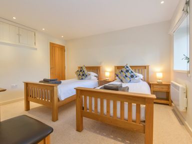 A bedroom with two wooden single beds bedside tables with lamps and a window at Old Armoury Barn Ashburton