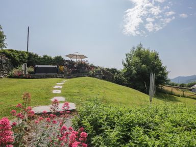 A garden with a seating area and flowers at Rose Cottage in Broughton-In-Furness
