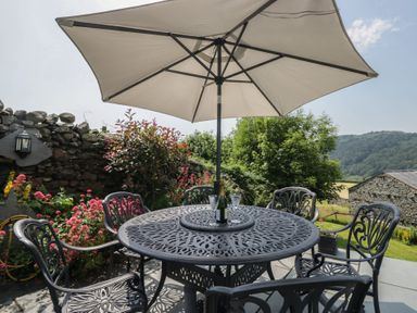 An outdoor seating area with a table and umbrella at Rose Cottage in Broughton-In-Furness