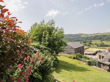A garden with flowers and stone buildings at Rose Cottage Broughton-In-Furness