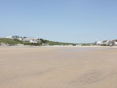 A wide sandy beach with buildings and green hills in the background at Seashore House in Porth