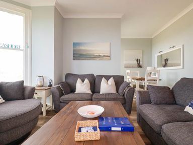 A living room with sofa, coffee table and dining area at Seashore House in Porth