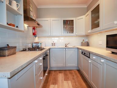 A kitchen with cabinets and a gas stove at Seashore House in Porth