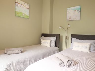 A bedroom with two beds and paintings on the wall at Seashore House in Porth