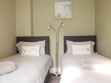 A bedroom with two beds and a lamp at Seashore House in Porth
