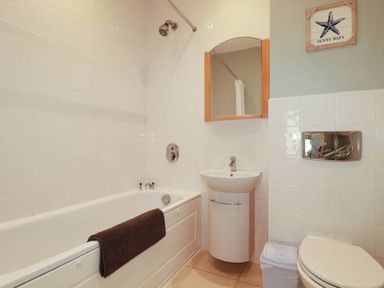 A bathroom with a bathtub, sink, and toilet at Seashore House in Porth