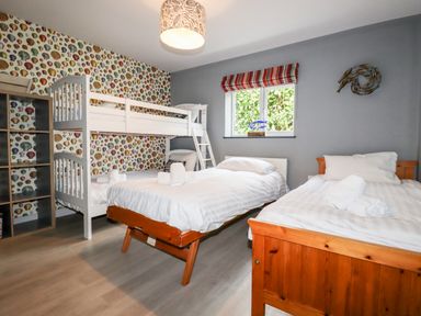 A bedroom with bunk beds single beds and a window at Trenant View in Wadebridge