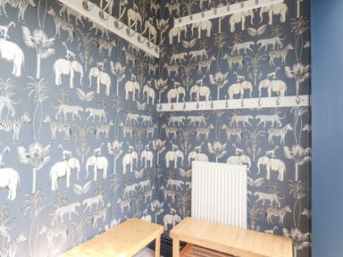 A corner of a room with animal wallpaper a radiator wooden benches and wall hooks at Trenant View in Wadebridge