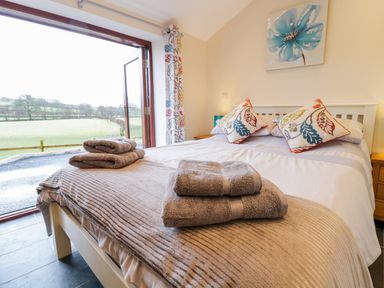 A bedroom with a bed with folded towels and a view of fields outside at Bothi in Llanuwchllyn