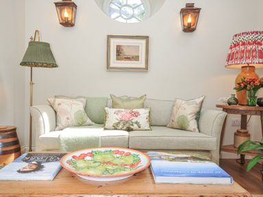 A living room with a sofa, table and lamp at The Coach House at Pendower House Fowey
