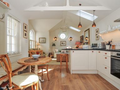 A kitchen with appliances and seating area at The Coach House at Pendower House Fowey