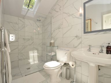 A bathroom with a shower, toilet, and sink at The Coach House at Pendower House in Fowey