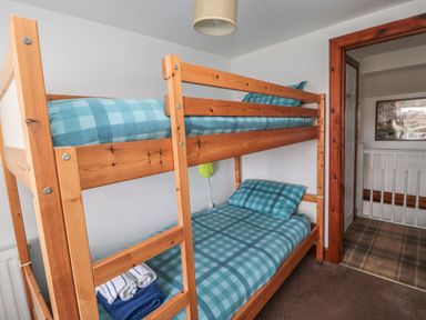 A bedroom with a wooden bunk bed and blue checkered bedding at Chillingham Cottage in Belford