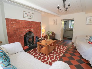A living room with a brick fireplace wooden coffee table two sofas and a patterned rug at Pengraig near Tregaron