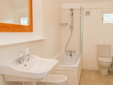 A bathroom with a sink and mirror a bathtub with a shower and a toilet at The Old Farmhouse Upper Pitts in Knighton