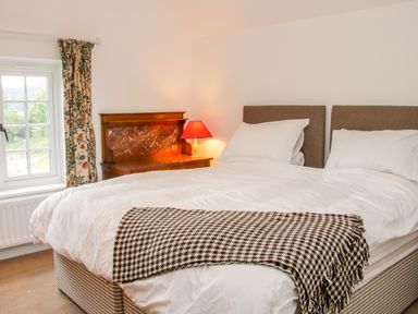 A bedroom with a bed with white bedding and a checkered blanket at The Old Farmhouse Upper Pitts in Knighton
