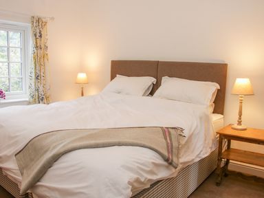 A bedroom with a double bed white bedding bedside tables and lamps at The Old Farmhouse Upper Pitts in Knighton