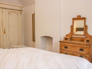 A bedroom with a wooden dresser and mirror and a white wardrobe at The Old Farmhouse Upper Pitts Knighton