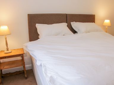 A bedroom with a double bed white bedding and two bedside tables with lamps at The Old Farmhouse Upper Pitts in Knighton
