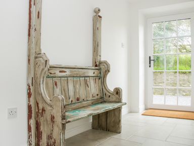 An old wooden bench with peeling paint next to a glass door with a view outside at The Old Farmhouse upper Pitts in Knighton